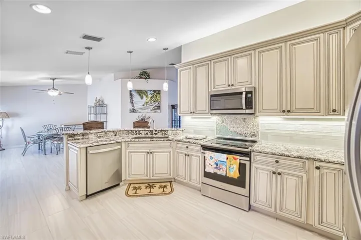 Kitchen featuring cream cabinets, appliances with stainless steel finishes, a peninsula, pendant lighting, and recessed lighting