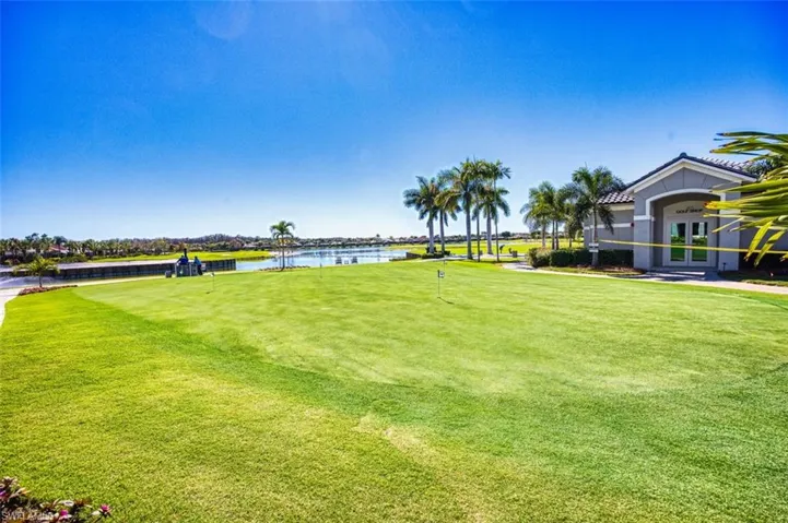 View of green lawn with a water view, golf course view, and a putting area