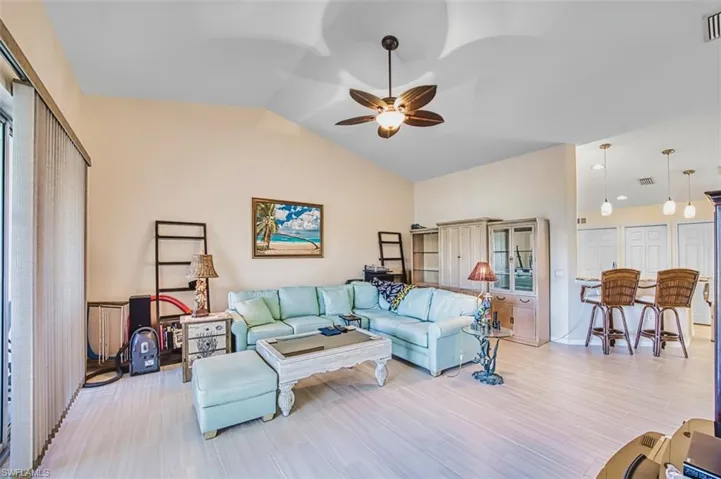Living area featuring a ceiling fan, vaulted ceiling, and light wood-style flooring
