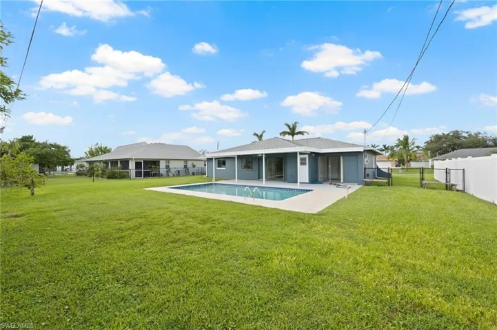 Back of house featuring a patio, a yard, and a fenced in pool