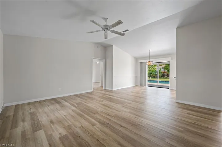 Unfurnished living room featuring light wood-type flooring, vaulted ceiling, and ceiling fan