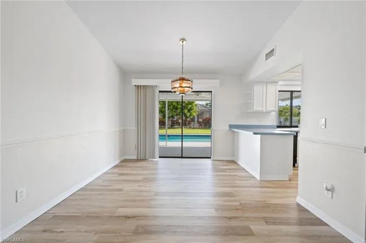 Unfurnished dining area featuring light wood-type flooring, lofted ceiling, a chandelier, and a wealth of natural light