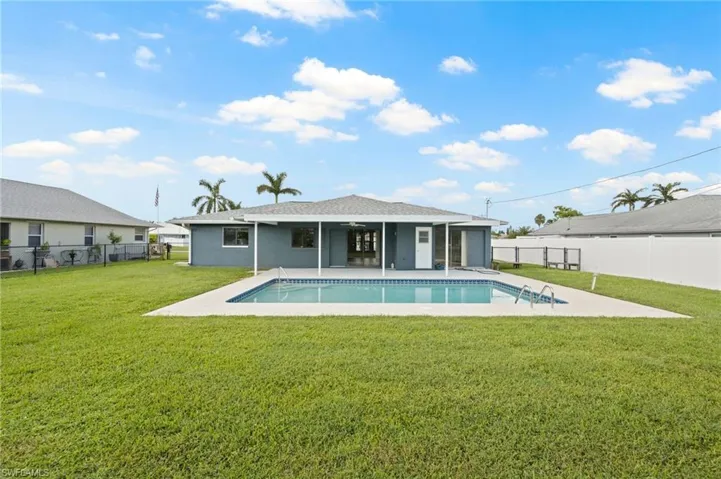 Rear view of house featuring a fenced in pool, a yard, and a patio area