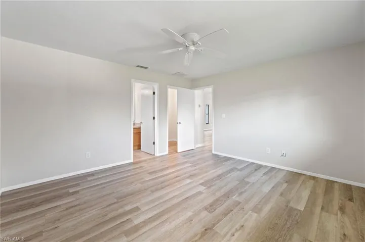 Unfurnished bedroom with ceiling fan, ensuite bathroom, and light hardwood / wood-style flooring