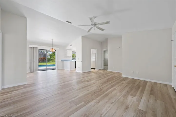 Unfurnished living room featuring light wood-type flooring, vaulted ceiling, and ceiling fan