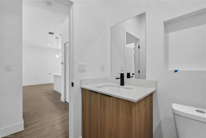 Modern vanity with wood-finish cabinetry, white countertop, and integrated sink