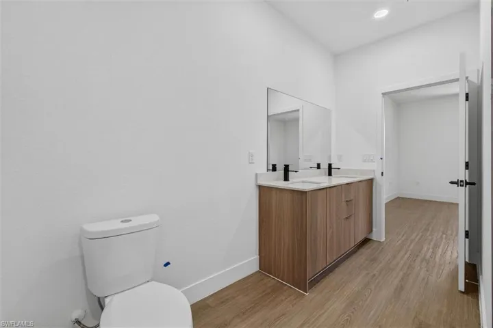 Bathroom featuring a dual vanity with a light-toned countertop, wood-finish cabinetry, and matte black fixtures