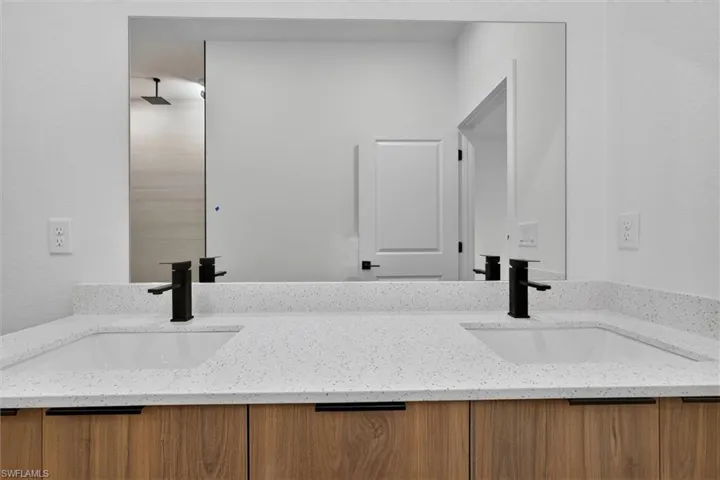 Dual undermount sinks set within a speckled white countertop and wood-finish cabinetry
