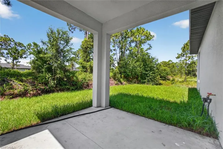 Covered concrete patio with columns and a verdant lawn