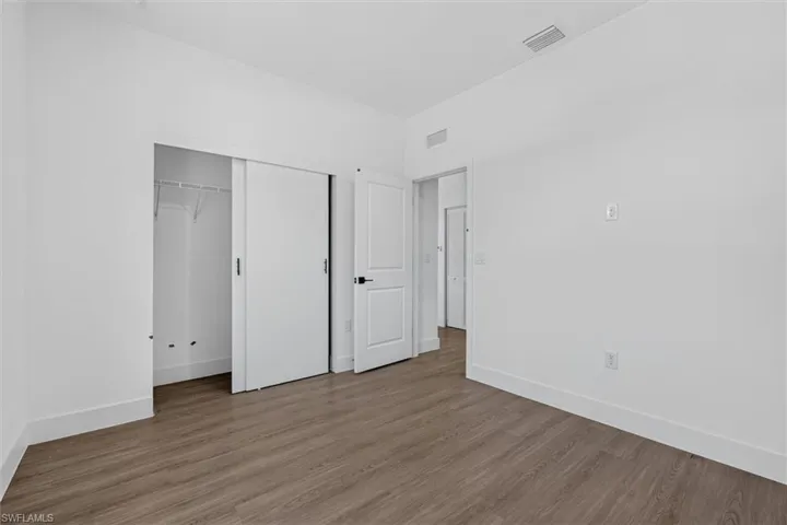Room featuring wood-finish flooring, white walls, and white baseboards