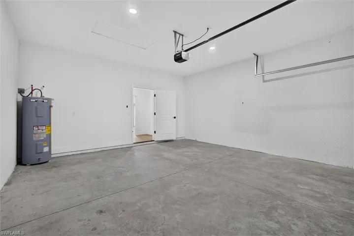 Spacious garage featuring a concrete floor, bright white walls, recessed lighting, and a water heater