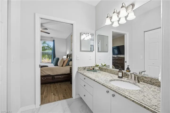 Bathroom with ensuite bath, light marble finish flooring, vanity, and ceiling fan