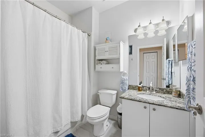 Full bath with curtained shower, vanity, and light marble finish floors