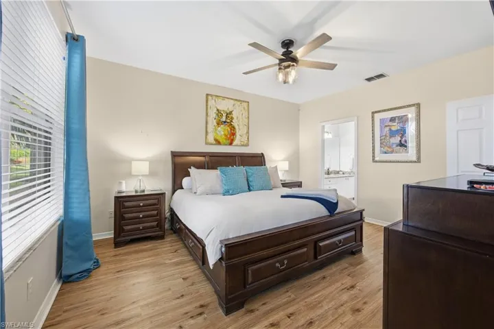 Bedroom featuring light wood-style flooring, ceiling fan, and ensuite bathroom