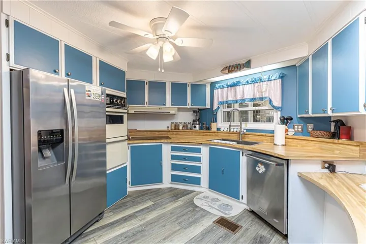Kitchen featuring sink, blue cabinets, stainless steel appliances, and wood counters