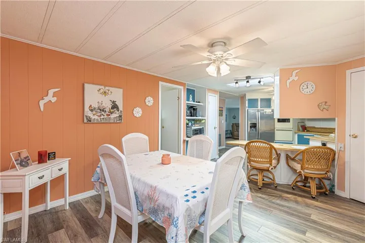 Dining space featuring ornamental molding, a textured ceiling, ceiling fan, wooden walls, and wood-type flooring