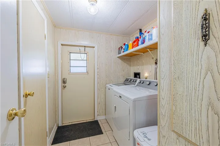Clothes washing area with light tile patterned flooring, a textured ceiling, crown molding, and washing machine and clothes dryer