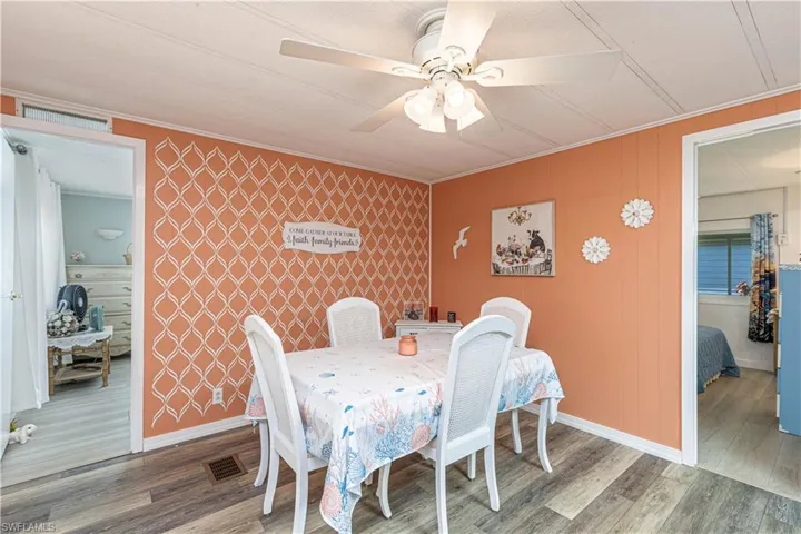 Dining area with ceiling fan, wood-type flooring, and ornamental molding