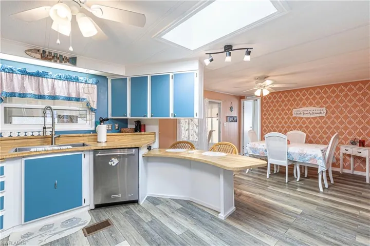 Kitchen featuring hardwood / wood-style floors, dishwasher, sink, a skylight, and kitchen peninsula