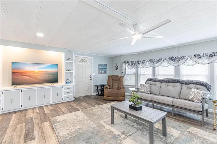 Living room featuring built in shelves, a textured ceiling, light hardwood / wood-style floors, and ceiling fan