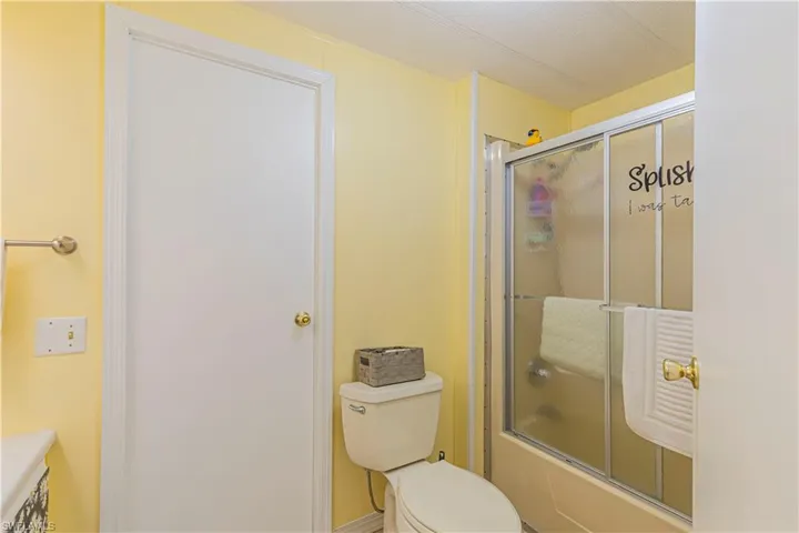 Bathroom with bath / shower combo with glass door and toilet