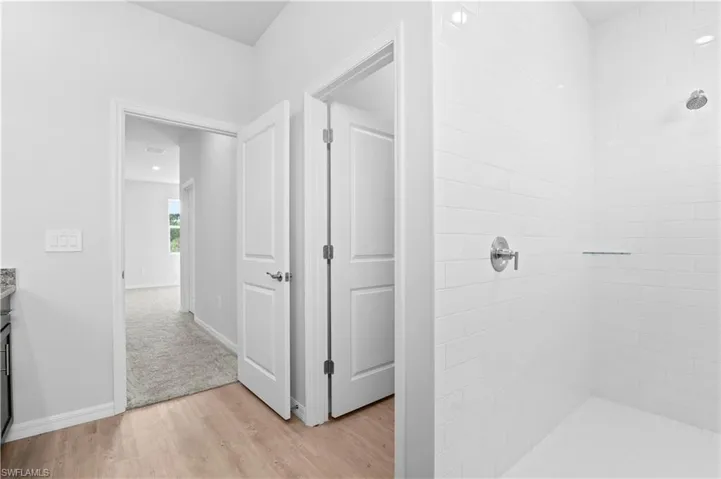 Full bathroom with light wood-type flooring, vanity, and a tile shower