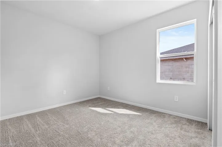 Unfurnished room with light colored carpet and baseboards