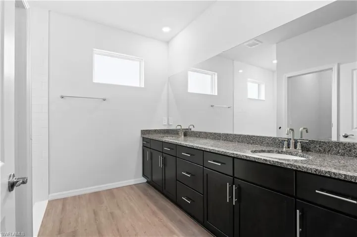 Bathroom featuring light wood-style floors, double vanity, and recessed lighting
