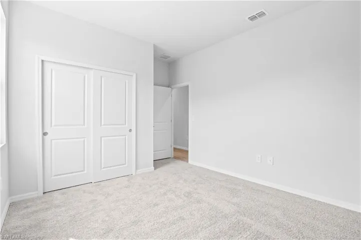 Unfurnished bedroom featuring light carpet and a closet