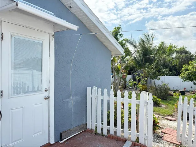 Doorway to property with fence and stucco siding