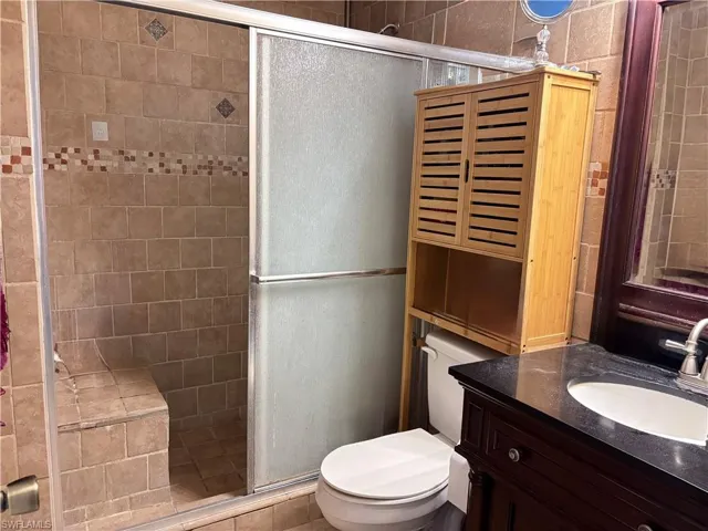 Bathroom with vanity, a shower stall, and toilet