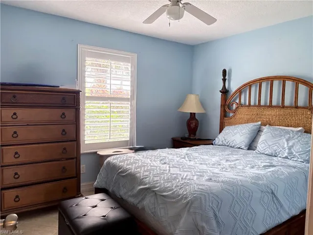Bedroom with a textured ceiling, ceiling fan, and light tile patterned flooring