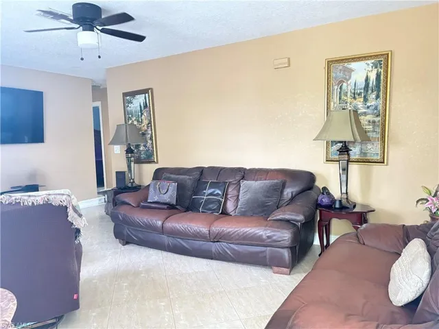 Living room featuring a ceiling fan and a textured ceiling