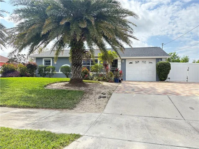 Single story home featuring a garage, fence, decorative driveway, stucco siding, and a front lawn