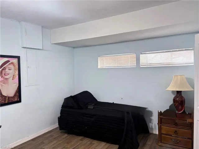 Bedroom with multiple windows, baseboards, and wood finished floors