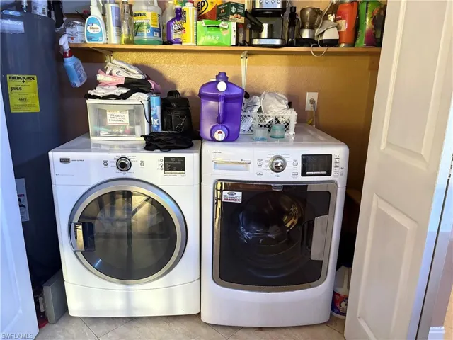 Laundry area with laundry area, water heater, washer and clothes dryer, and light tile patterned flooring
