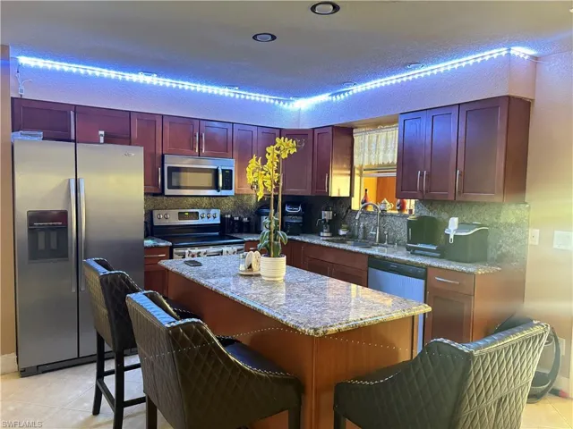 Kitchen featuring light tile patterned floors, dark brown cabinets, stainless steel appliances, and a sink