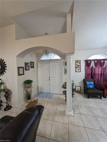 Foyer featuring light tile patterned flooring, ornate columns, and high vaulted ceiling