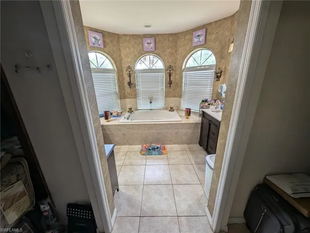 Bathroom featuring a garden tub, tile patterned flooring, and vanity