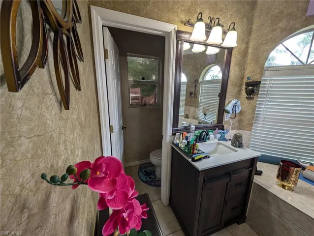 Full bathroom with vanity, tile patterned flooring, and a textured wall