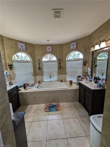 Bathroom featuring a bath, vanity, tile patterned floors, and tile walls