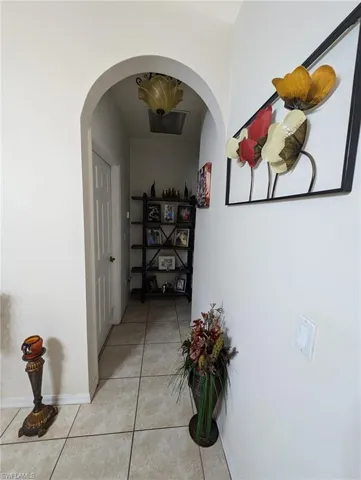 Hallway with arched walkways and light tile patterned floors