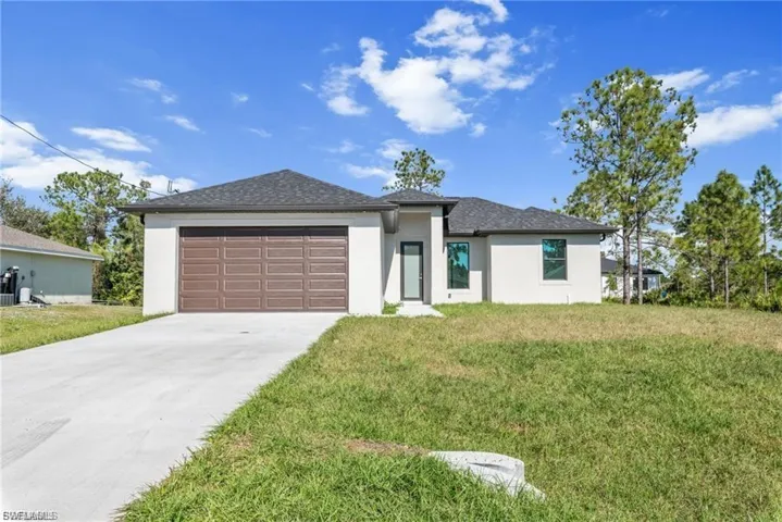 Prairie-style house with stucco siding, concrete driveway, a front yard, an attached garage, and a shingled roof