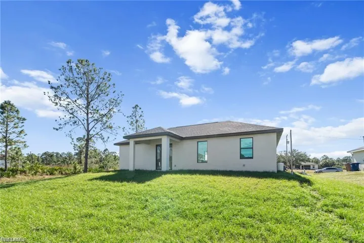 Rear view of property featuring stucco siding and a lawn