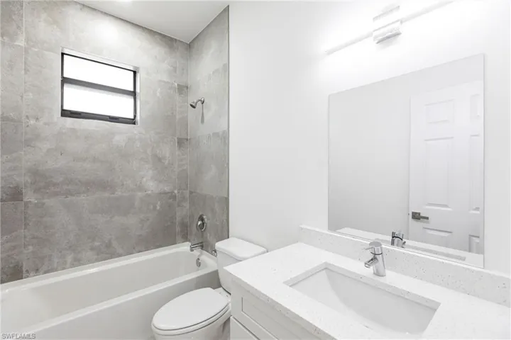 Full bathroom with toilet, vanity, and tiled shower / bath