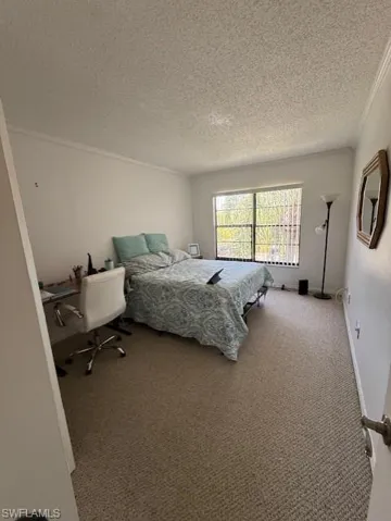 Carpeted bedroom featuring a textured ceiling and crown molding