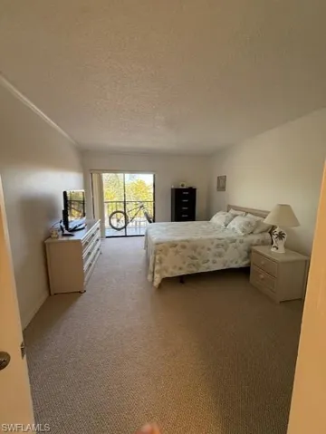 Bedroom featuring access to outside, dark colored carpet, and a textured ceiling