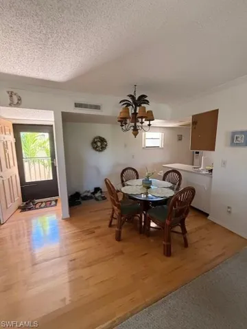 Dining room with suspended lighting, a textured ceiling, and light wood-style flooring