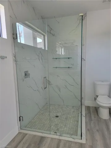 Bathroom with a shower with door, toilet, and hardwood / wood-style flooring