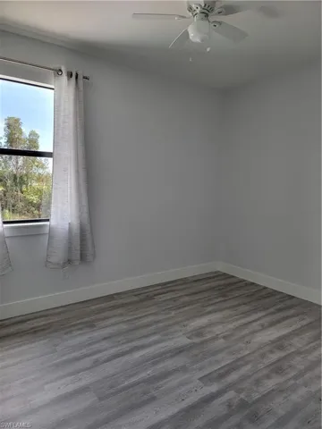 Unfurnished room with dark wood-type flooring and ceiling fan